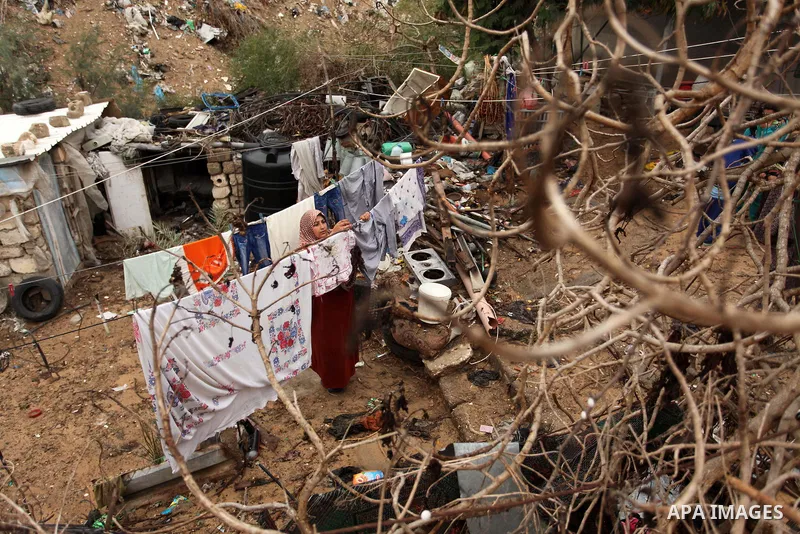 A Palestinian woman hangs laundry on a rope to dry outside her dwelling in Khan Younis in the southern Gaza Strip December 19, 2016. Photo by Ashraf Amra