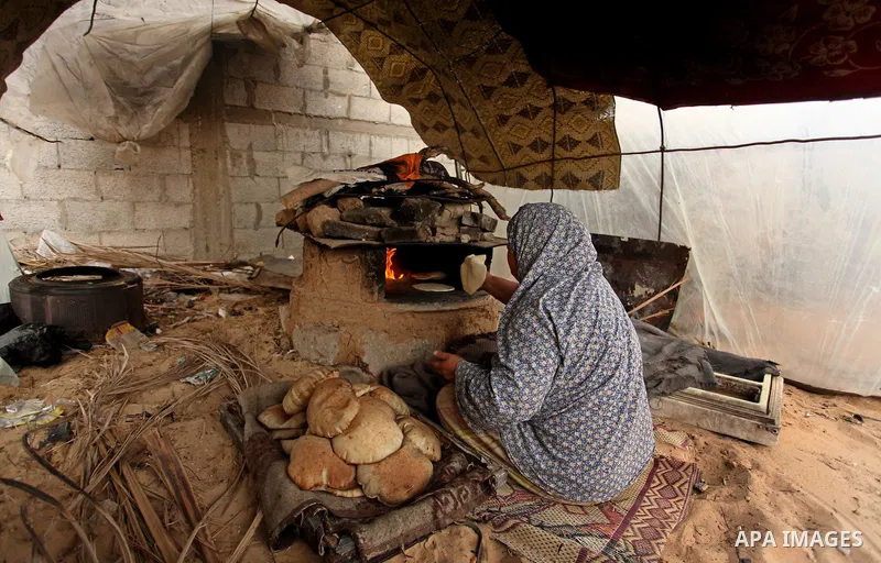 A Palestinian woman bakes bread in a tent outside her dwelling in Khan Younis in the southern Gaza Strip December 19, 2016. Photo by Ashraf Amra