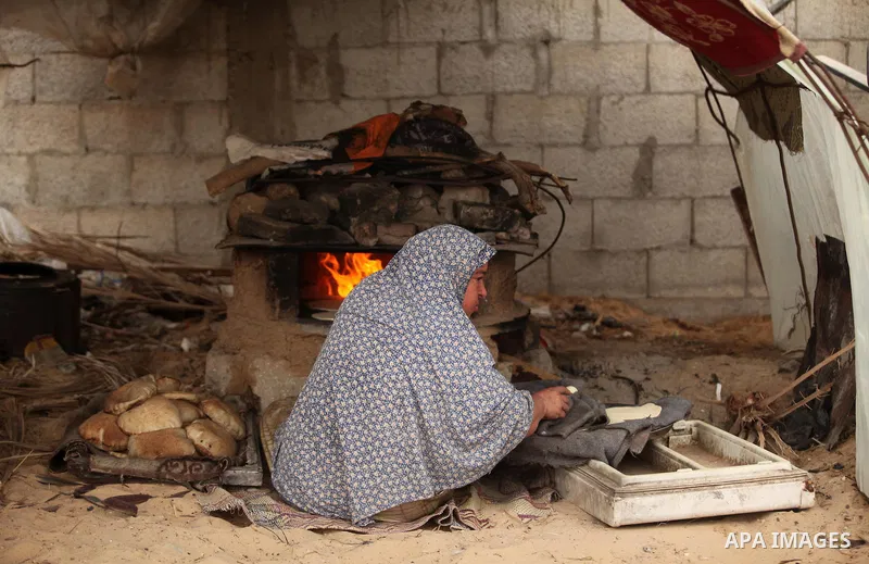 A Palestinian woman bakes bread in a tent outside her dwelling in Khan Younis in the southern Gaza Strip December 19, 2016. Photo by Ashraf Amra