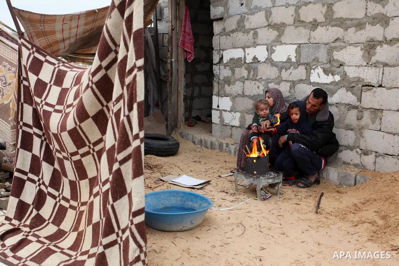 Palestinians warm themselves around a fire outside their dwellings in Khan Younis in the southern Gaza Strip December 19, 2016. Photo by Ashraf Amra