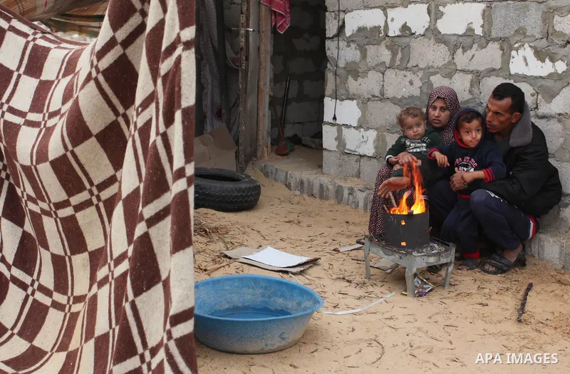 Palestinians warm themselves around a fire outside their dwellings in Khan Younis in the southern Gaza Strip December 19, 2016. Photo by Ashraf Amra