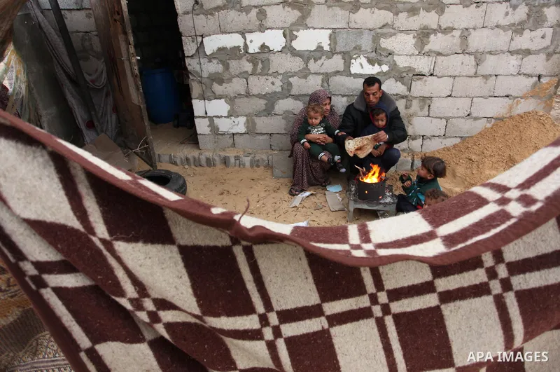 Palestinians warm themselves around a fire outside their dwellings in Khan Younis in the southern Gaza Strip December 19, 2016. Photo by Ashraf Amra
