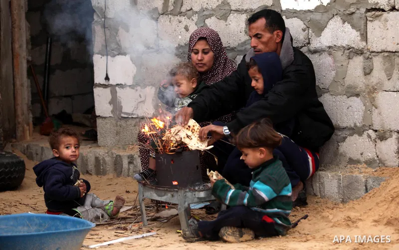 Palestinians warm themselves around a fire outside their dwellings in Khan Younis in the southern Gaza Strip December 19, 2016. Photo by Ashraf Amra