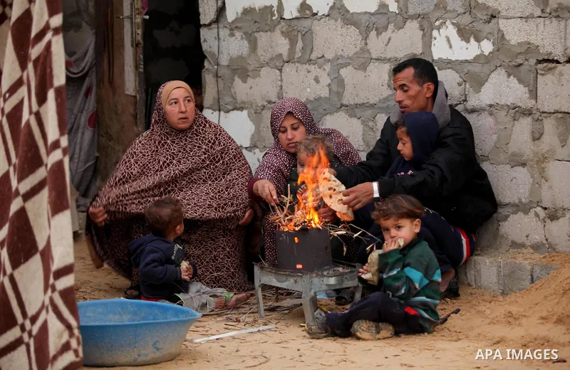 Palestinians warm themselves around a fire outside their dwellings in Khan Younis in the southern Gaza Strip December 19, 2016. Photo by Ashraf Amra