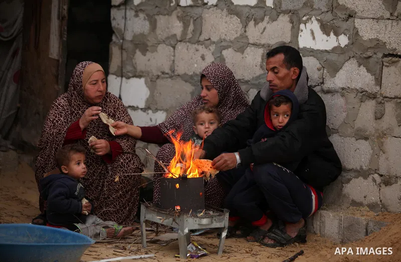 Palestinians warm themselves around a fire outside their dwellings in Khan Younis in the southern Gaza Strip December 19, 2016. Photo by Ashraf Amra