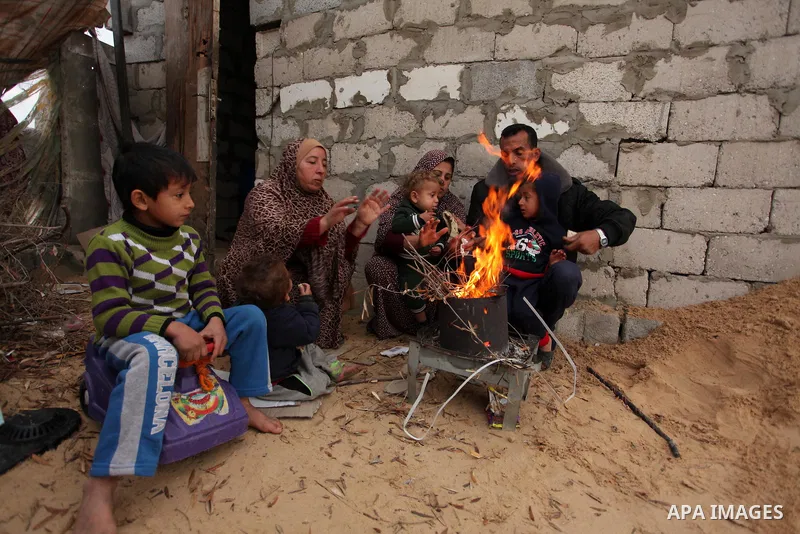 Palestinians warm themselves around a fire outside their dwellings in Khan Younis in the southern Gaza Strip December 19, 2016. Photo by Ashraf Amra