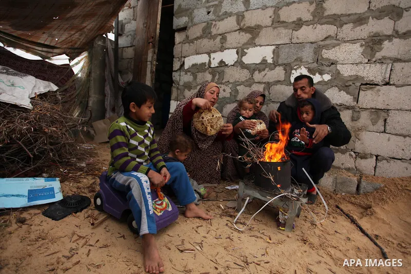 Palestinians warm themselves around a fire outside their dwellings in Khan Younis in the southern Gaza Strip December 19, 2016. Photo by Ashraf Amra