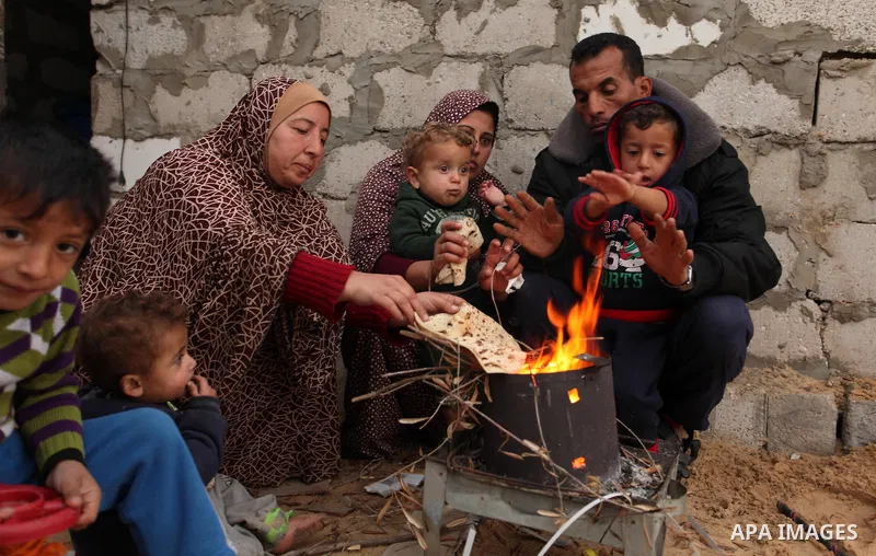 Palestinians warm themselves around a fire outside their dwellings in Khan Younis in the southern Gaza Strip December 19, 2016. Photo by Ashraf Amra