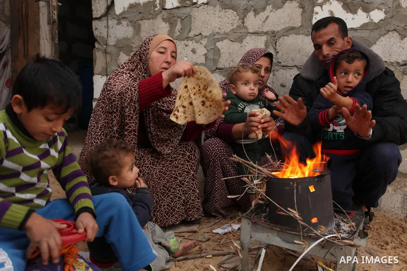 Palestinians warm themselves around a fire outside their dwellings in Khan Younis in the southern Gaza Strip December 19, 2016. Photo by Ashraf Amra