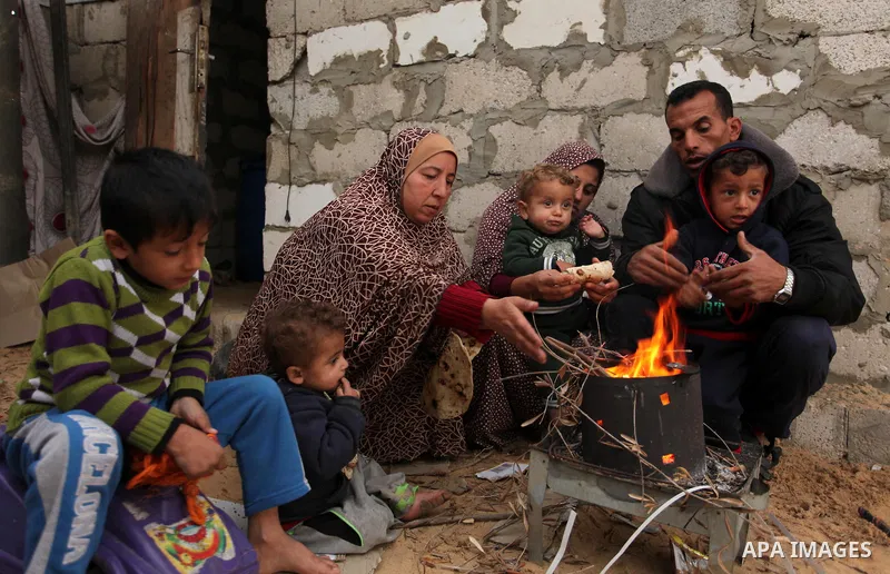 Palestinians warm themselves around a fire outside their dwellings in Khan Younis in the southern Gaza Strip December 19, 2016. Photo by Ashraf Amra