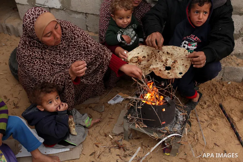 Palestinians warm themselves around a fire outside their dwellings in Khan Younis in the southern Gaza Strip December 19, 2016. Photo by Ashraf Amra