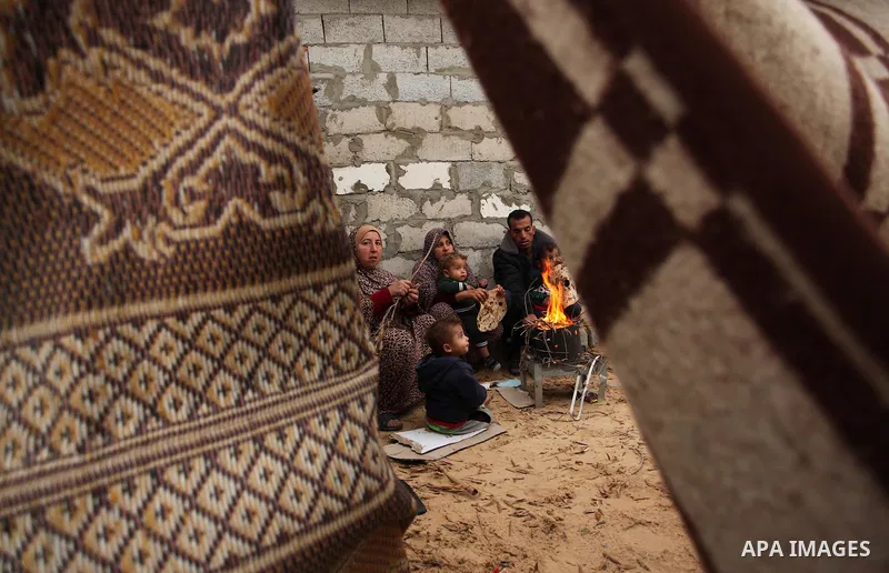 Palestinians warm themselves around a fire outside their dwellings in Khan Younis in the southern Gaza Strip December 19, 2016. Photo by Ashraf Amra
