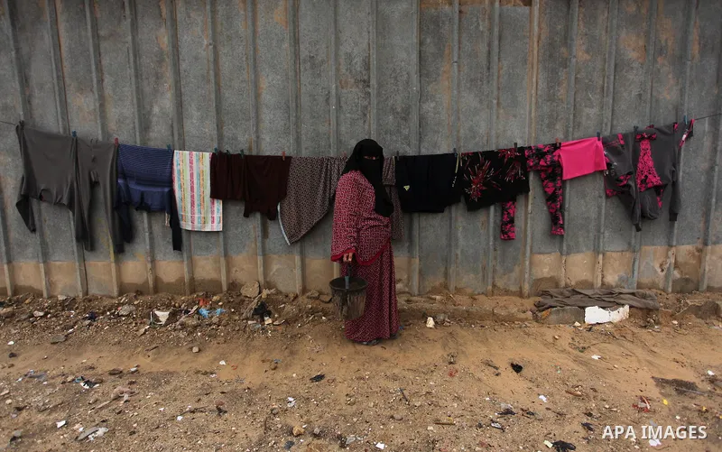 A Palestinian woman hangs laundry on a rope to dry outside her dwelling in Khan Younis in the southern Gaza Strip December 19, 2016. Photo by Ashraf Amra