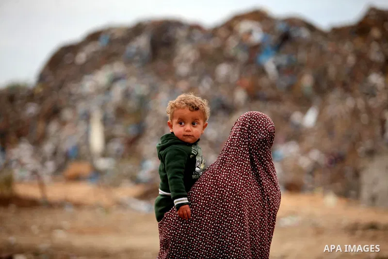 A Palestinian woman carries her son outside her dwelling in Khan Younis in the southern Gaza Strip December 19, 2016. Photo by Ashraf Amra