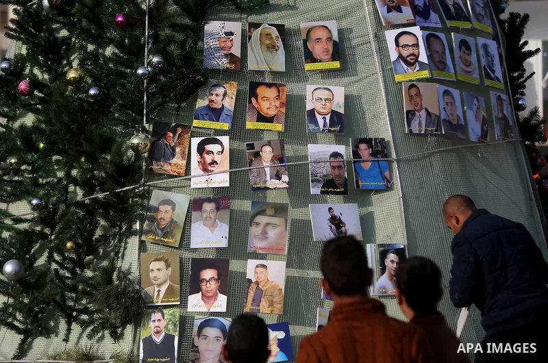 Palestinian youths use pictures of Palestinian martyrs to decorate a Christmas tree, in the West Bank town of al-Azariya, east of Jerusalem, on December 22, 2016. Photo by Shadi Hatem