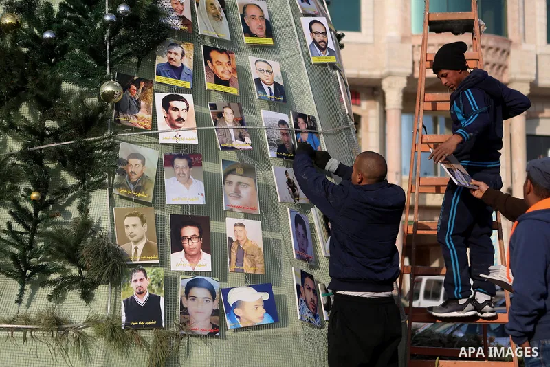 Palestinian youths use pictures of Palestinian martyrs to decorate a Christmas tree, in the West Bank town of al-Azariya, east of Jerusalem, on December 22, 2016. Photo by Shadi Hatem