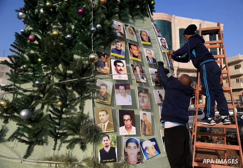 Palestinian youths use pictures of Palestinian martyrs to decorate a Christmas tree, in the West Bank town of al-Azariya, east of Jerusalem, on December 22, 2016. Photo by Shadi Hatem