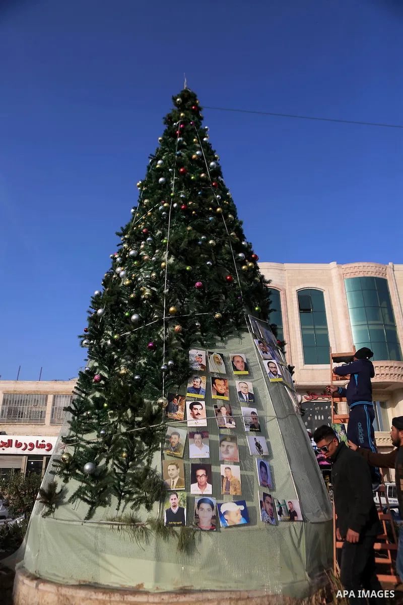 Palestinian youths use pictures of Palestinian martyrs to decorate a Christmas tree, in the West Bank town of al-Azariya, east of Jerusalem, on December 22, 2016. Photo by Shadi Hatem