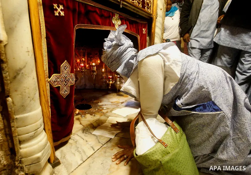 Africans Christian pilgrims look to a 14-point silver star on the marble floor of the Grotto in the Church of the Nativity, believed to be the birthplace of Jesus Christ, in the West Bank city of Bethlehem on December 22...