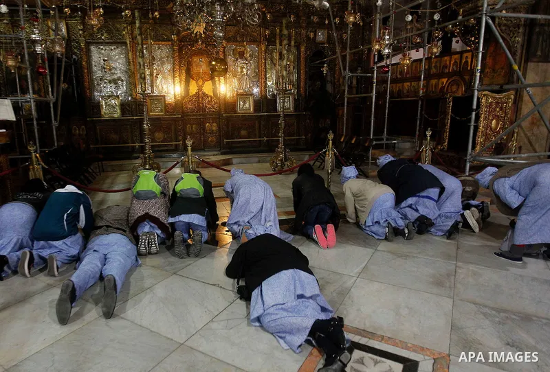 Africans Christian pilgrims pray at the Grotto in the Church of the Nativity, believed to be the birthplace of Jesus Christ, in the West Bank city of Bethlehem on December 22, 2016. Photo by Wisam Hashlamoun