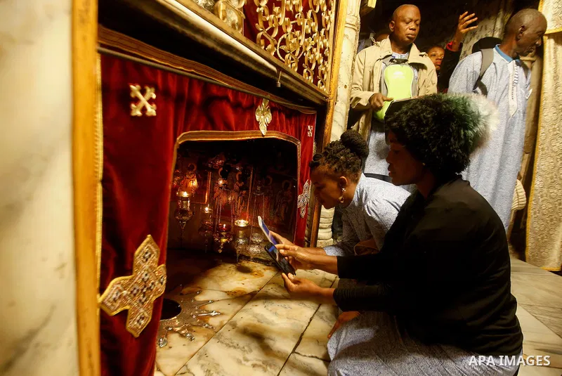 Africans Christian pilgrims take a photo to a 14-point silver star on the marble floor of the Grotto in the Church of the Nativity, believed to be the birthplace of Jesus Christ, in the West Bank city of Bethlehem on Dec...
