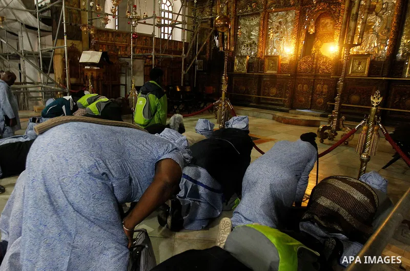 Africans Christian pilgrims pray at the Grotto in the Church of the Nativity, believed to be the birthplace of Jesus Christ, in the West Bank city of Bethlehem on December 22, 2016. Photo by Wisam Hashlamoun