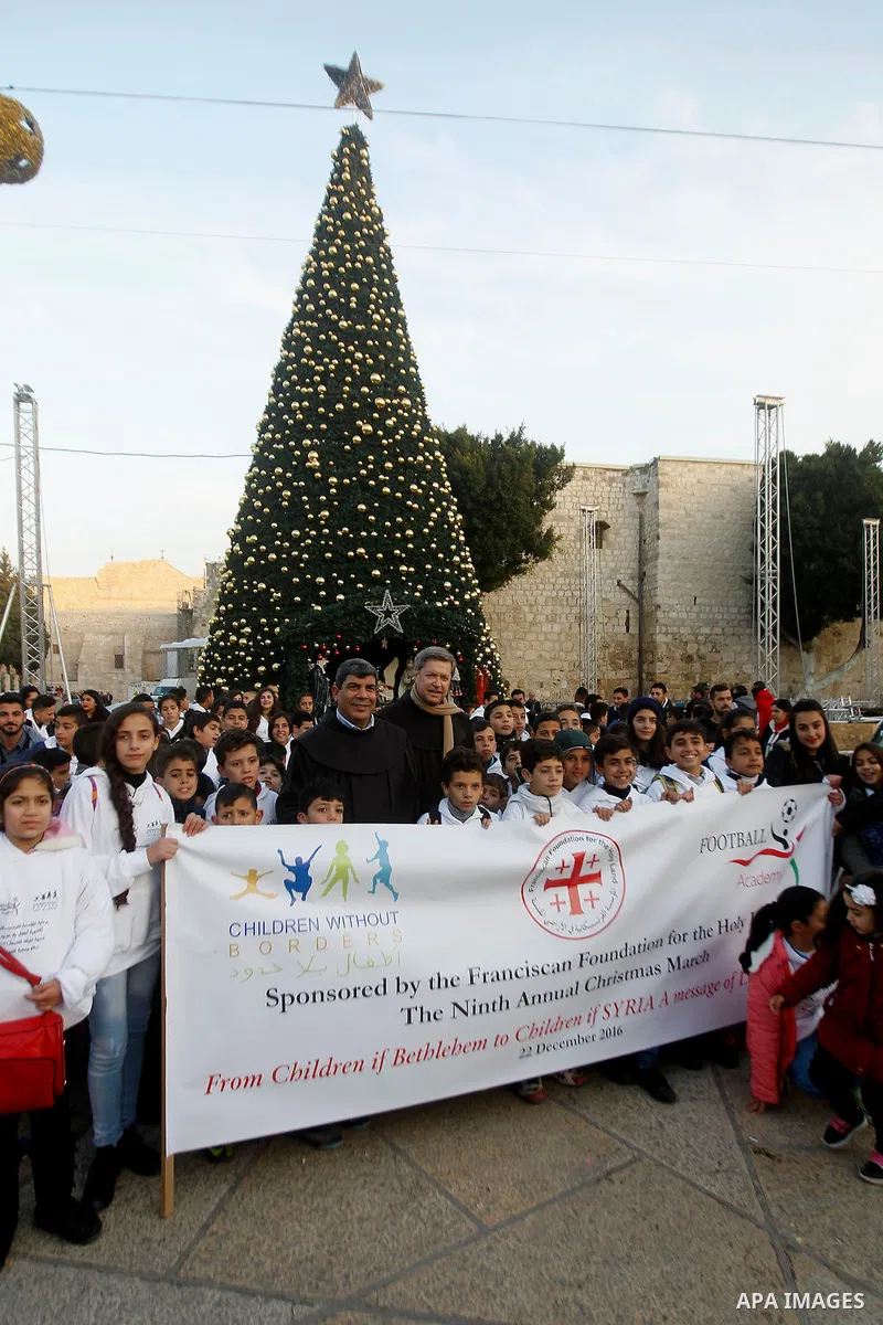 Palestinian Christian children take part at the ninth annual Christmas march past a Christmas tree at the Manger Square near the Church of the Nativity, revered as the site of Jesus Christ's birth, on December 22, 2016 i...