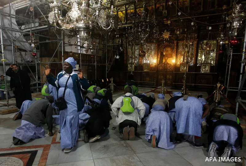 Africans Christian pilgrims pray at the Grotto in the Church of the Nativity, believed to be the birthplace of Jesus Christ, in the West Bank city of Bethlehem on December 22, 2016. Photo by Wisam Hashlamoun