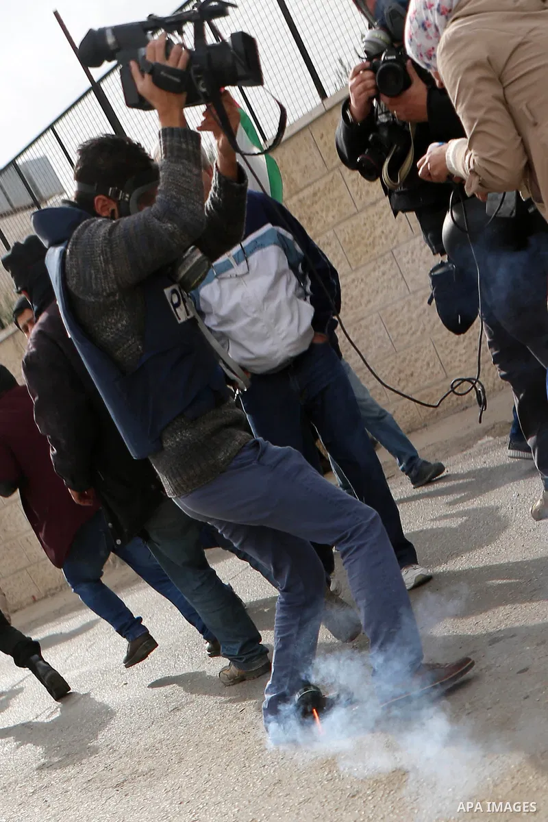 A Palestinian cameraman takes cover form a tear gas grenade fired by Israeli border guard during clashes at a demonstration next to a section of Israel's separation wall in the biblical town of Bethlehem, in the occupied...