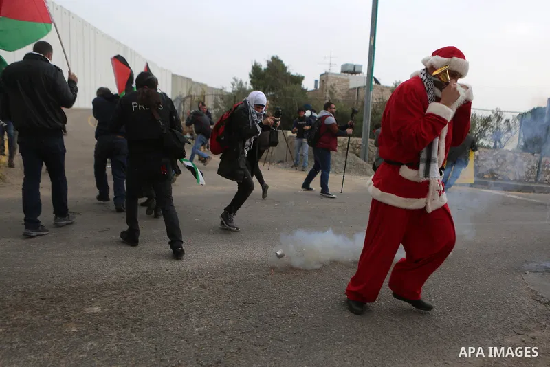 Palestinian protesters run for a cover form a tear gas grenade fired by Israeli border guard during clashes at a demonstration next to a section of Israel's separation wall in the biblical town of Bethlehem, in the occup...