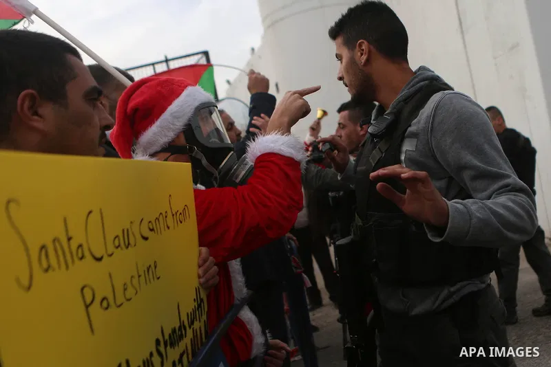 A Palestinian protester dressed up as Santa Claus argues with an Israeli border guard during clashes at a demonstration next to a section of Israel's separation wall in the biblical town of Bethlehem, in the occupied Wes...