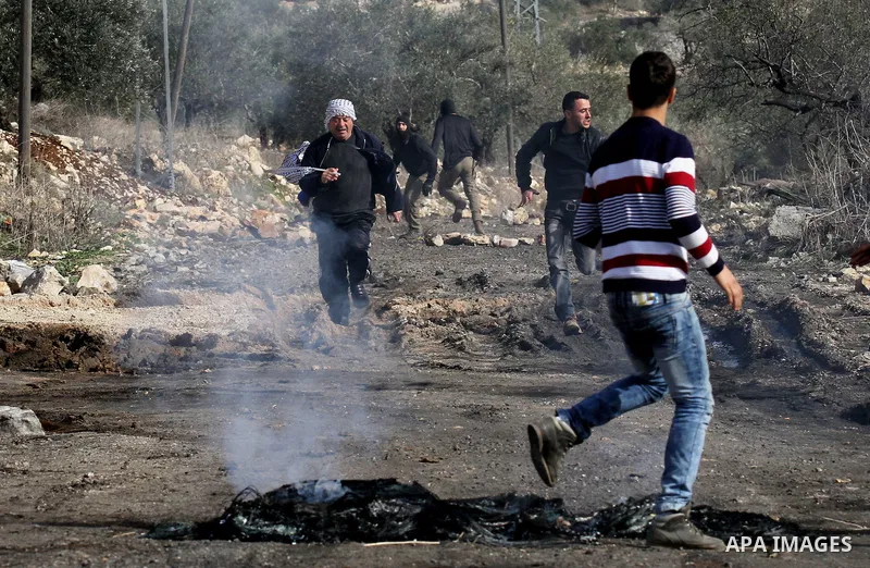 Palestinian protesters run during clashes with Israeli security forces following a demonstration against the expropriation of Palestinian land by Israel in the village of Kfar Qaddum, in the occupied West Bank, on Decemb...
