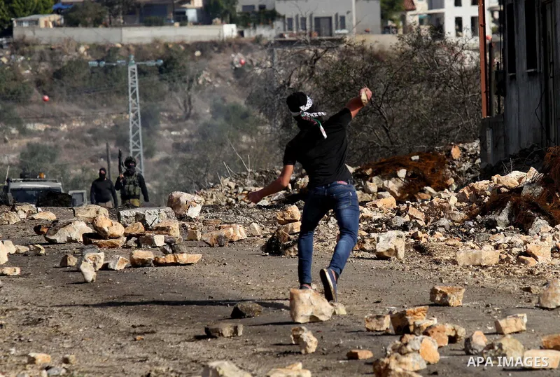 A Palestinian protester hurls stones toward Israel security forces during clashes following a demonstration against the expropriation of Palestinian land by Israel in the village of Kfar Qaddum, in the occupied West Bank...