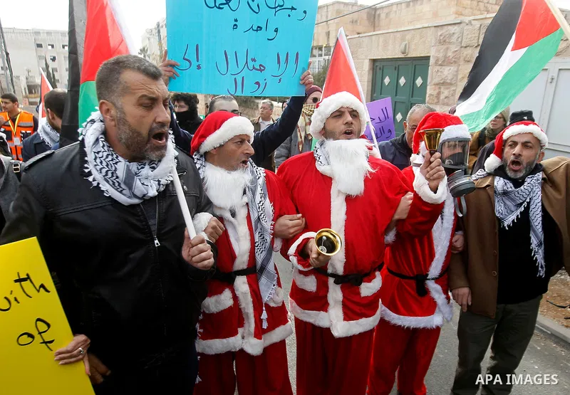 Palestinian demonstrators holding Palestinian flags take part in a protest next to a gate at a section of Israel's separation wall in the biblical town of Bethlehem, in the occupied West Bank, on December 23, 2016. Photo...