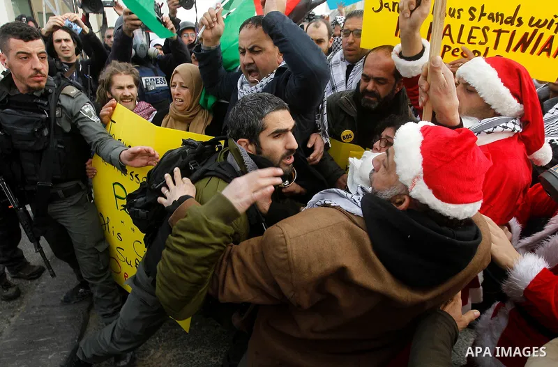 An Israeli border policeman scuffles with a Palestinian protester dressed up as Santa Claus during clashes at a demonstration next to a section of Israel's separation wall in the biblical town of Bethlehem, in the occupi...