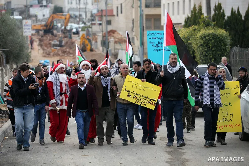 Palestinian demonstrators holding Palestinian flags take part in a protest next to a gate at a section of Israel's separation wall in the biblical town of Bethlehem, in the occupied West Bank, on December 23, 2016. Photo...