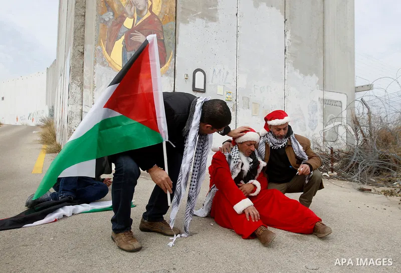 A Palestinian protester dressed up as Santa Claus reacts after inhaling tear gas fired by Israeli border guard during clashes at a demonstration next to a section of Israel's separation wall in the biblical town of Bethl...