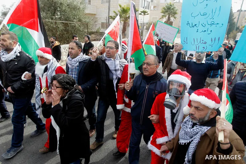 Palestinian demonstrators holding Palestinian flags take part in a protest next to a gate at a section of Israel's separation wall in the biblical town of Bethlehem, in the occupied West Bank, on December 23, 2016. Photo...