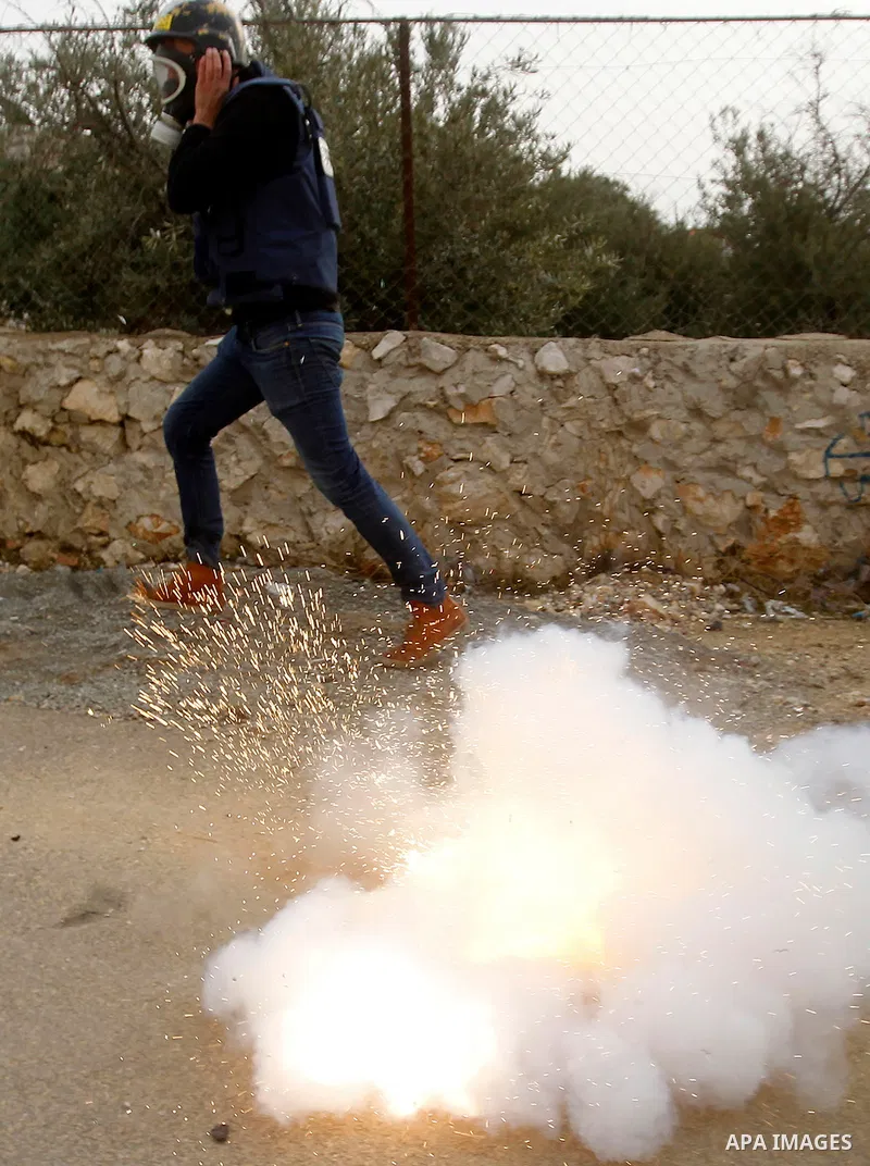 A Palestinian Journalist runs for cover form tear gas fired by fired by Israeli border guard during clashes at a demonstration next to a section of Israel's separation wall in the biblical town of Bethlehem, in the occup...