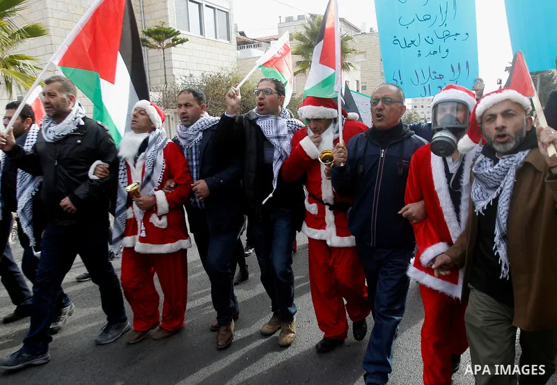 Palestinian demonstrators holding Palestinian flags take part in a protest next to a gate at a section of Israel's separation wall in the biblical town of Bethlehem, in the occupied West Bank, on December 23, 2016. Photo...