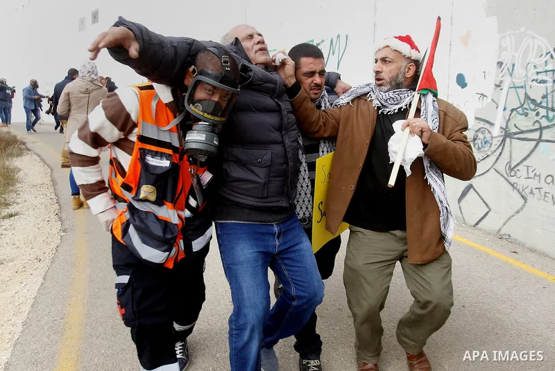 A Palestinian cameraman is evacuated after inhaling tear gas fired by fired by Israeli border guard during clashes at a demonstration next to a section of Israel's separation wall in the biblical town of Bethlehem, in th...
