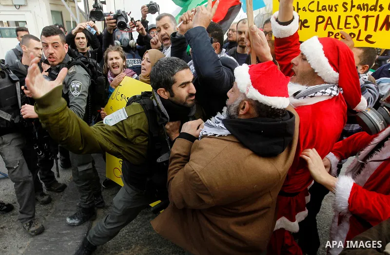An Israeli border policeman scuffles with a Palestinian protester dressed up as Santa Claus during clashes at a demonstration next to a section of Israel's separation wall in the biblical town of Bethlehem, in the occupi...