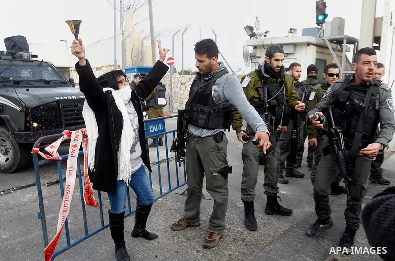 A Palestinian woman demonstrates next to a gate at a section of Israel's separation wall in the biblical town of Bethlehem, in the occupied West Bank, on December 23, 2016. Photo by Wisam Hashlamoun