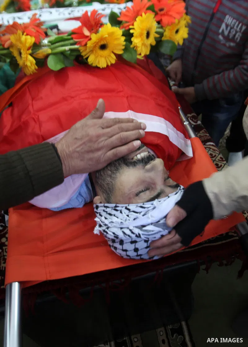Mourners gather around the body of Palestinian Jihad Khalil, who according to the Israeli police was shot and killed by an Israeli security guard after Khalil tried to stab him last November, during his funeral after Isr...