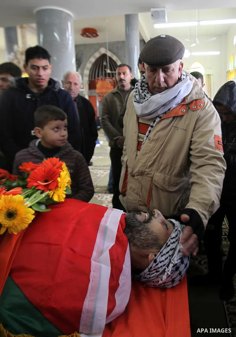 Mourners gather around the body of Palestinian Jihad Khalil, who according to the Israeli police was shot and killed by an Israeli security guard after Khalil tried to stab him last November, during his funeral after Isr...