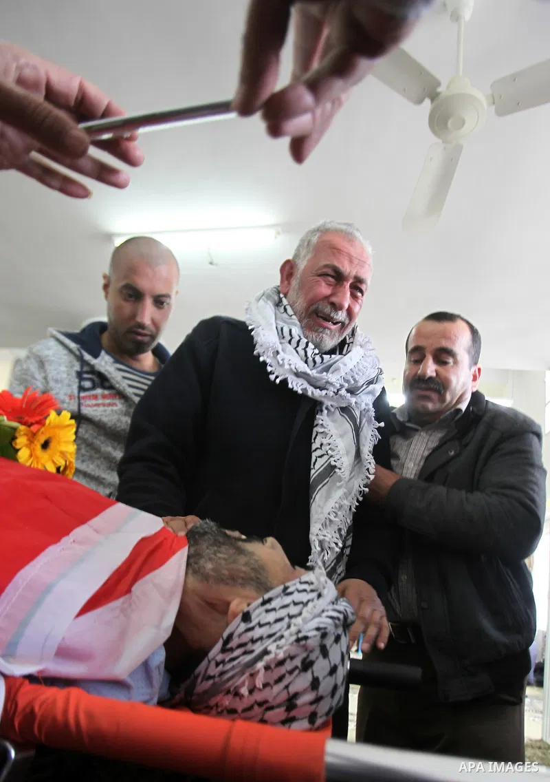 Mourners gather around the body of Palestinian Jihad Khalil, who according to the Israeli police was shot and killed by an Israeli security guard after Khalil tried to stab him last November, during his funeral after Isr...