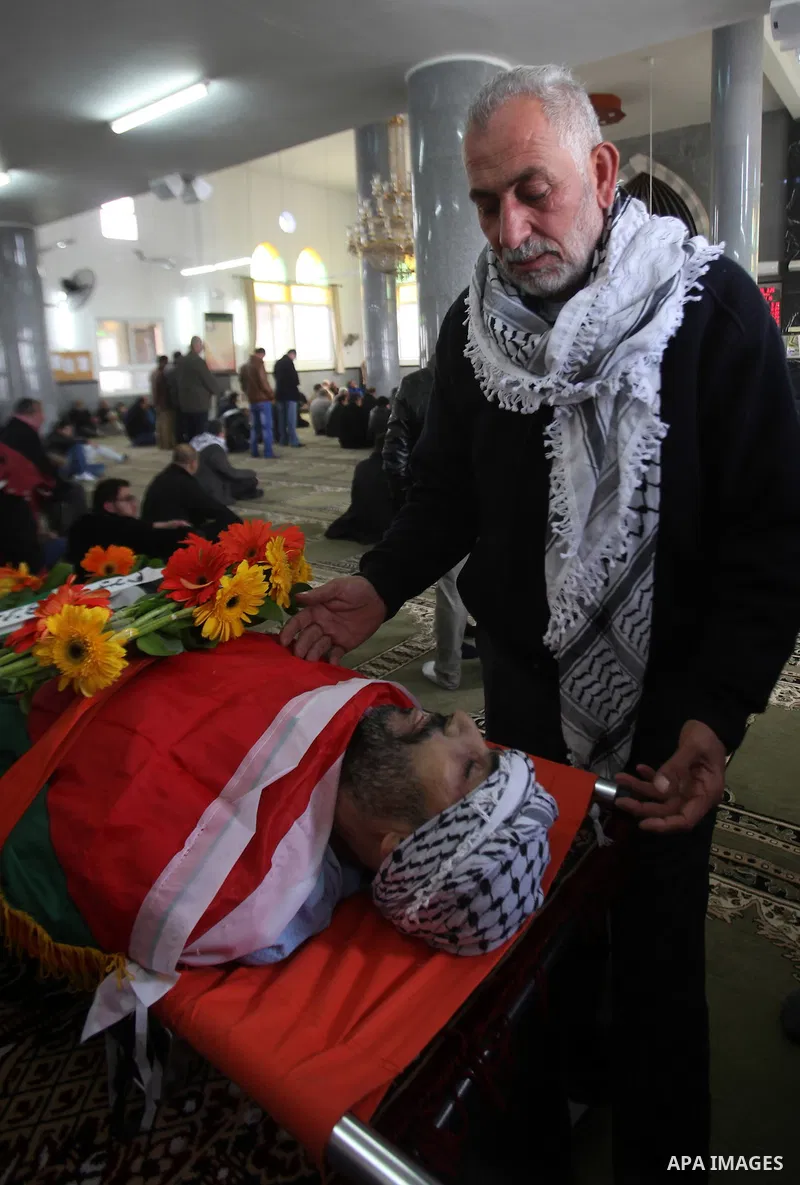 Mourners gather around the body of Palestinian Jihad Khalil, who according to the Israeli police was shot and killed by an Israeli security guard after Khalil tried to stab him last November, during his funeral after Isr...