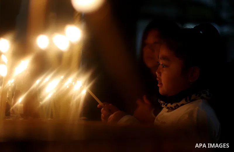 A visitor lights a candle inside the Church of the Nativity in the West Bank town of Bethlehem December 24, 2016. Photo by Shadi Hatem