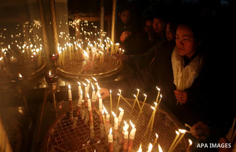 A visitor lights a candle inside the Church of the Nativity in the West Bank town of Bethlehem December 24, 2016. Photo by Shadi Hatem