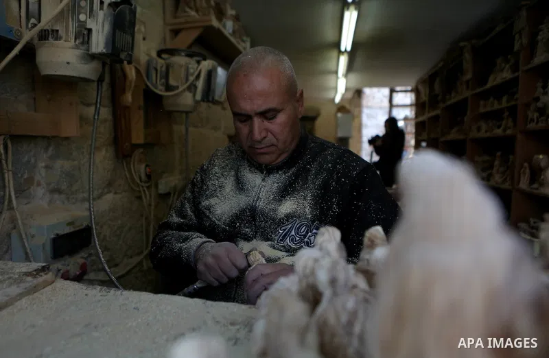 A Palestinian carpenter carves a wooden effigies of the the Holy Family at a workshop in the West Bank town of Bethlehem, on December 26, 2016. The traditional birthplace of Jesus Christ prepares to celebrate Christmas....